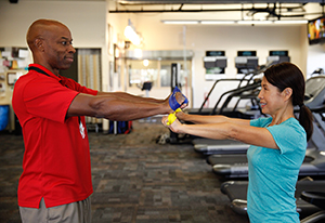 Physical therapist showing woman resistance band exercise.