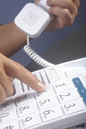 Closeup of hands pressing button on large-button phone.