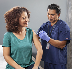 Healthcare provider giving woman injection in arm.