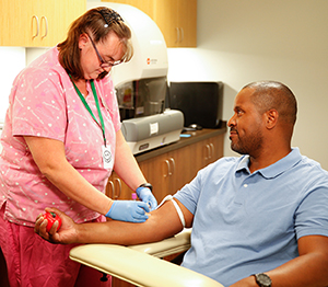 Healthcare provider drawing blood from man's arm.