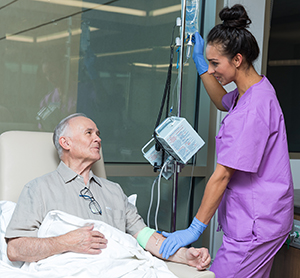 Healthcare provider caring for man having infusion treatment.