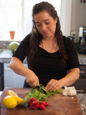 Woman chopping fresh vegetables in kitchen.