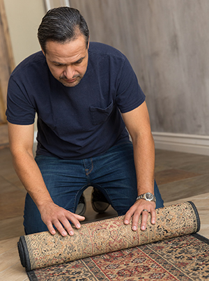 Man rolling up throw rug.