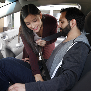 Woman helping man in car buckle seatbelt.