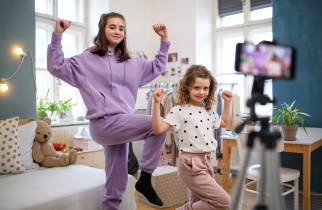 Pre-teen and younger sibling exercise while video taping themselves for social media