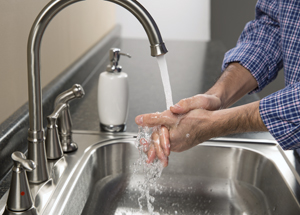 Close-up of hands at sink washing in running water.