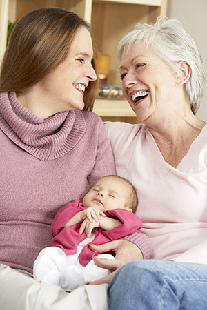 New mother and grandmother holding newborn baby daughter.