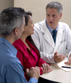 Man and woman sitting at desk talking to health care provider.