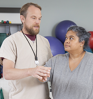 Physical therapist working with woman's arm.